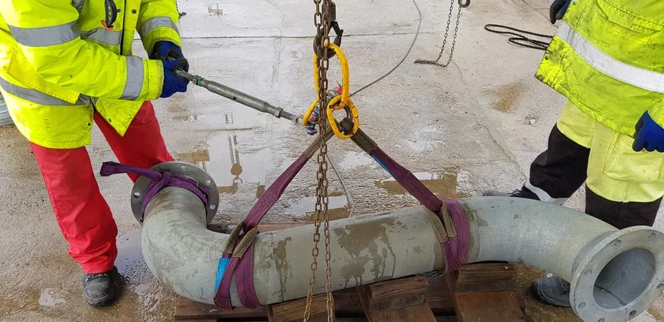 Riggers move the pipe using two chain blocks Stock Photos
