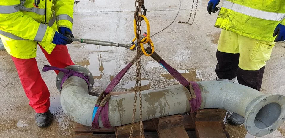 Riggers move the pipe using two chain blocks Stock Photos