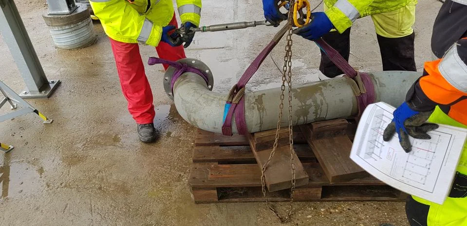 Riggers move the pipe using two chain blocks Stock Photos