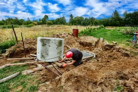 Rigging work to move concrete ring during septic tank installation. Stock Photos