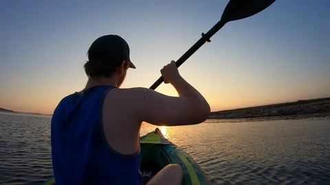 Right behind shot: Man paddling his kayak and gliding towards the setting sun Stock Footage 112186802