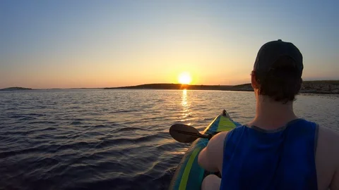 Right behind shot: young man paddling a kayak at sunset Stock Footage 112188514