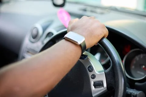 The right hand of a black man on the steering wheel of a car Stock Photos