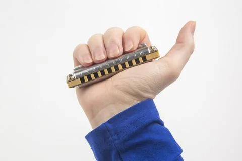 The right hand holds a harmonica on a white background. Classical musical win Stock Photos