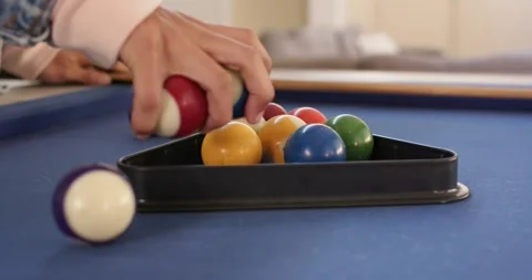 Right hand lowering rack onto blue felt pool table, pressing balls into triangle Stock Footage 339590885
