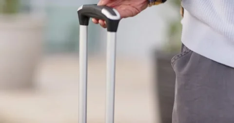 Right hand pressing button on suitcase at terminal entrance extending telescopic Stock Footage 344339738