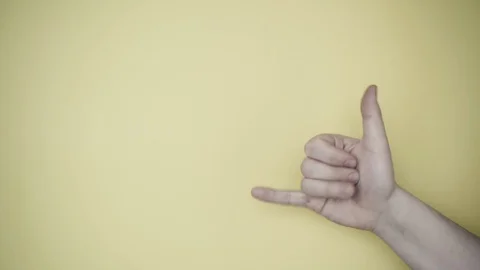 Right hand shows a gesture: let's drink! Yellow background. Close up 스톡 동영상 128986217