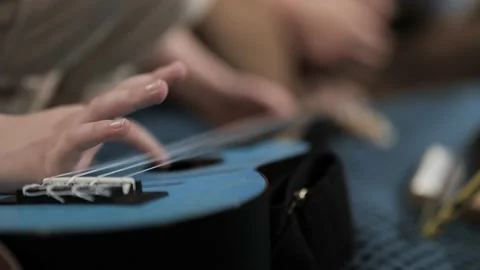 Right hand of small child pulls strings on ukulele. Kid playing ukulele Видео 238602531