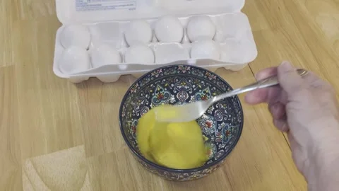 Right hand stirs eggs in blue patterned bowl Stock Footage 340112181