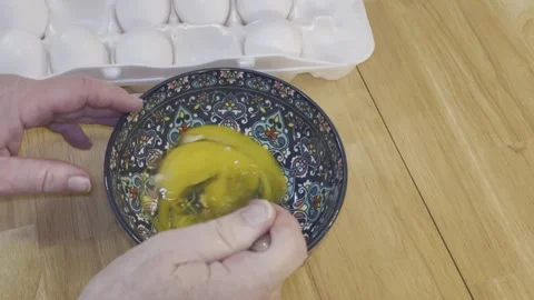 Right Hand Stirs Scrambles Raw Eggs in a Blue Floral Patterned Bowl Stock Footage 340112125