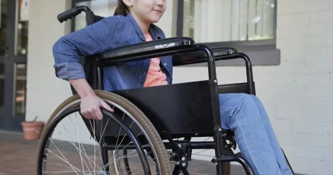 Right hand touching rim is initiating teen female pushing manual wheelchair Stock Footage 342392518