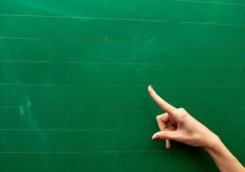 Right hand of a young girl pointing at the center of a green school board Stock Photos