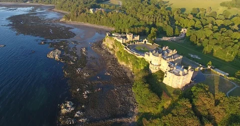 Right to Left Distant Drone Shot of a Scottish Castle near a Woods Stock Footage 97380356
