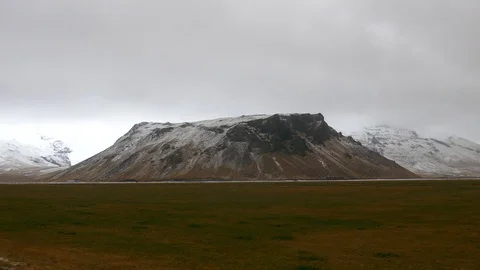 Right to left pan of beautiful meadow, snowy mountain cloudy sky in background Stock Footage 93615906