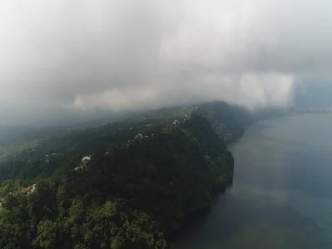 Right-left pan near clouds, over small town and lake in Bali Indonesia. Stock Footage 80144734