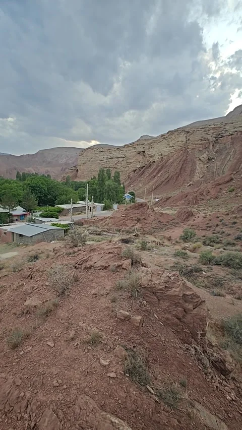 Right to left pan over stunning scenery red mountains with forest village in the Video stock 311568492