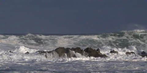 Right pan of a rocky reef as foaming high waves gather and break over it Stock Footage 59526838