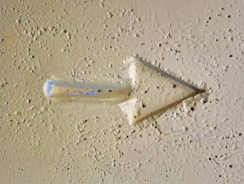 A right-pointing arrow pressed into yellow-painted concrete Foto stock