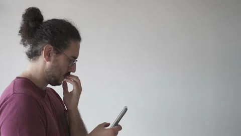 Right side medium shot of young man looking at smartphone and biting his nails Stock Footage 161551994