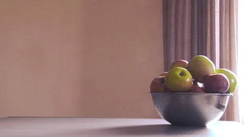 On the right side of the table there is a metal bowl with apples on which Vídeo Stock 105378985