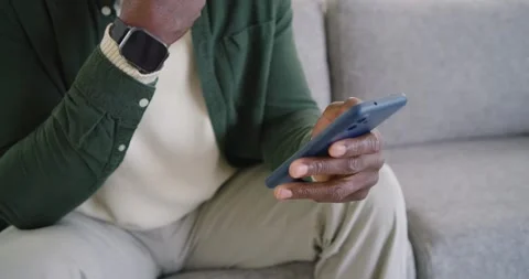Right thumb is initiating taps as hands are swiping blue phone on gray sofa, Stock Footage 345822708