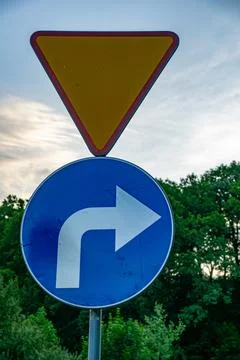 A Right Turn Warning Sign With a Yield Sign Above It Stock Photos