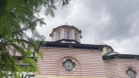 Rila Monastery emerges through leafy trees beneath a cloudy mountain sky Stock-Footage 344478739