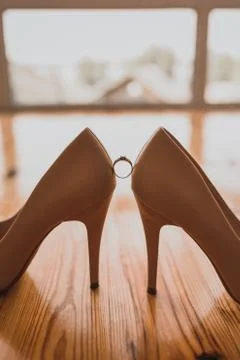A ring between two women's high heel shoes. Stock Photos