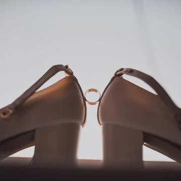 A ring between two women's high heel shoes. 写真素材
