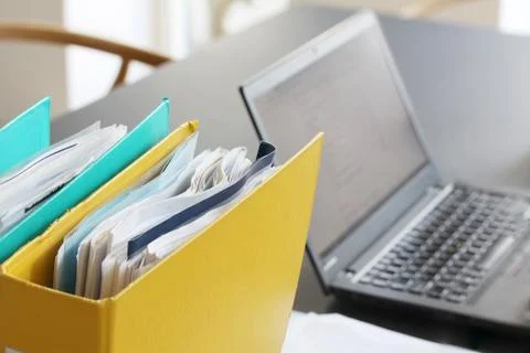 Ring binders filled with papers in front of laptop computer on table in offi Stock Photos
