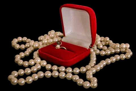 Ring in a box. Ring in the red box and a pearl necklace on a black background Stock Photos