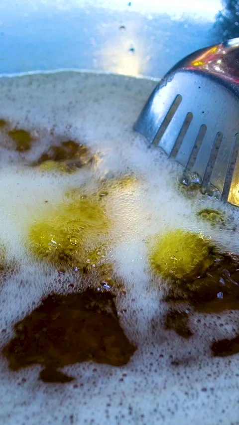 Ring donuts are fried in an automatic deep fryer in hot vegetable oil. 4K Stock Footage 313120493
