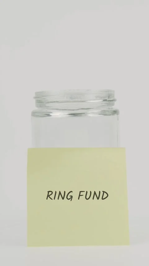 Ring fund text or word on yellow sticky note attached to glass jar with hand Stock Footage 311782074