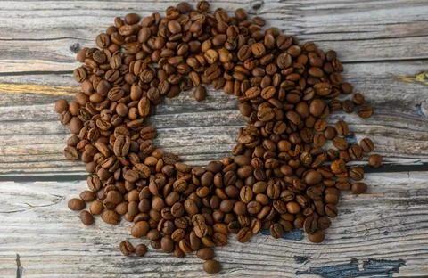 Ring layout of roasted coffee beans on light wooden texture top down Stock Photos