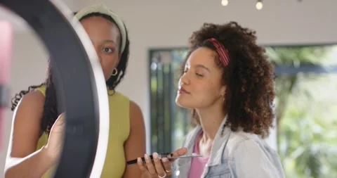 Ring light shifting revealing diverse female friends teaching makeup brush Stock Footage 340972784