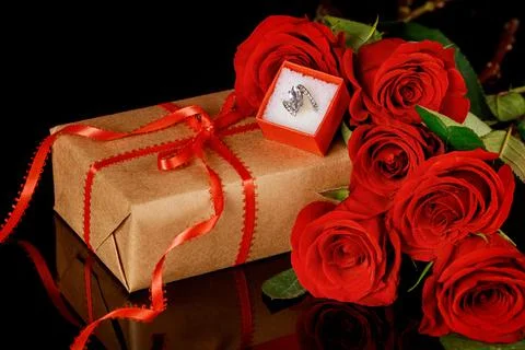 Ring in red box and beautiful red roses on black background. Valentines Day. Stock Photos