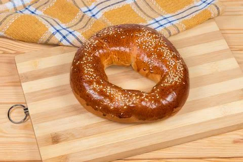 Ring shaped bread roll sprinkled with sesame on cutting board Stock Photos