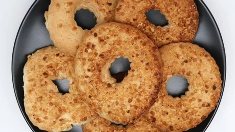 A Ring Of Shortbread Cookies With Peanuts Rotates On A Black Plate On White Back Stock Footage 240941835