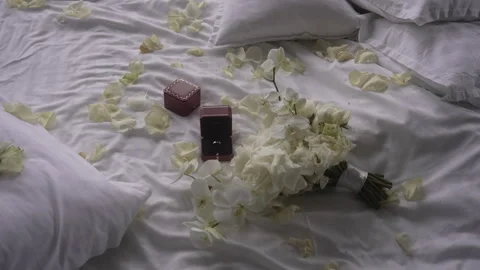 A ring sits in a box surrounded by flowers on the bed Vidéo 265573483