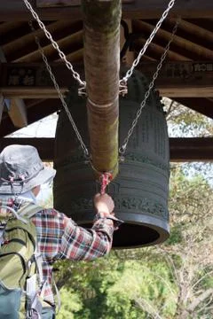 Ring a temple bell by a male hiker in Japan Stock Photos