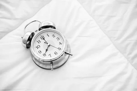 Ringing alarm clock on white bed sheet. Top view of object. 8 o clock sett... Stock Photos