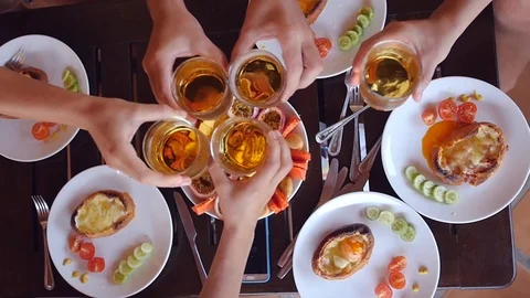 Ringing glass glasses with drinks on a background of food, top view. slow motion Stock Footage 89173093