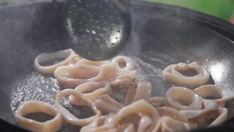 Rings of calamari are frying in the boiling oil on the open fire, grilling squid Stock Footage