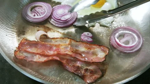 Rings of red onions fried in a pan with bacon and egg. Stock Footage 101751312
