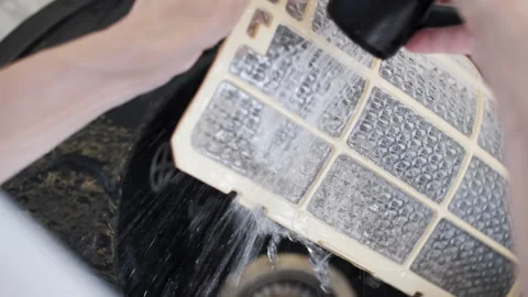 Rinsing dirty air conditioner filter with water for HVAC system care 库存影片 343960378