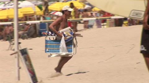 Rio de Janeiro: Man Carrying Lounge Chair on Beach Stock Footage 46970934