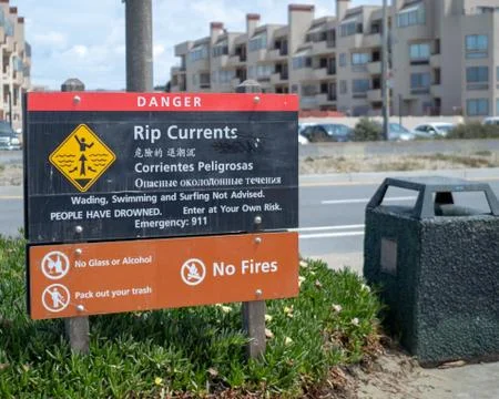 Rip current warning for an ocean area in multiple languages Stock Photos
