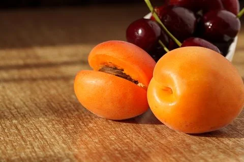 Ripe apricots are lying on the table, with a pitted seed visible Stock Photos