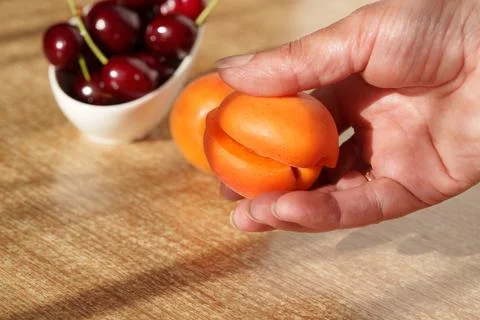 Ripe apricots are lying on the table, with a pitted seed visible Stock Photos