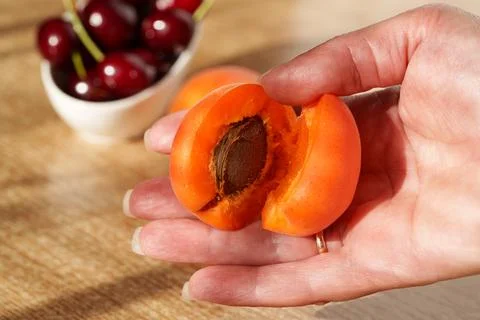 Ripe apricots are lying on the table, with a pitted seed visible Stock Photos